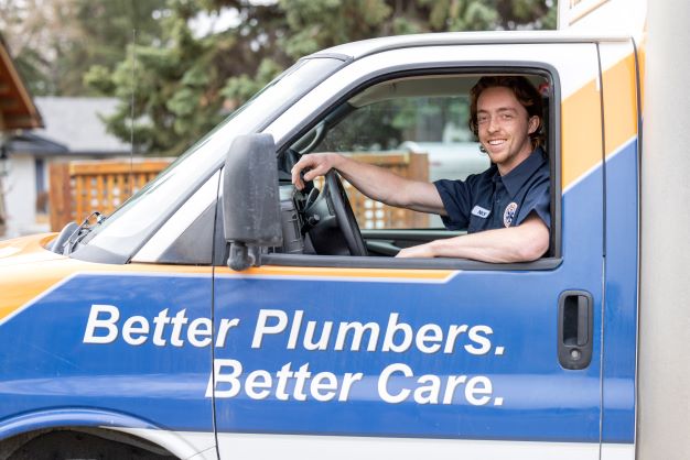 A cheerful plumber sits in a branded van and ready to go to setup Ductless Air Conditioner