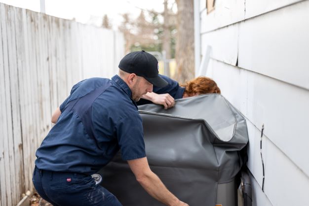 Two technicians are performing Air Conditioner Maintenance in Okotoks, AB