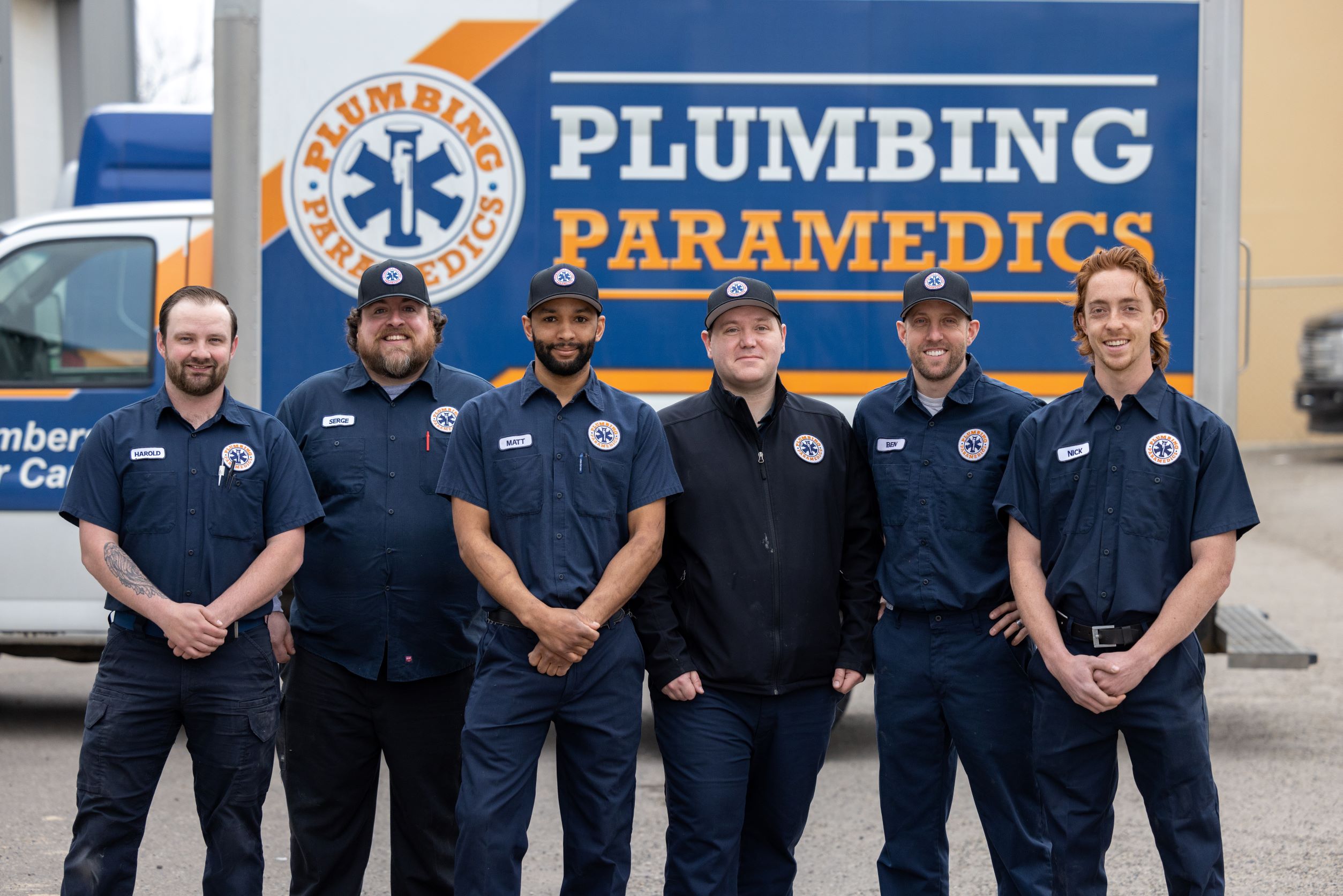 Six employees in uniform are standing before the company's van