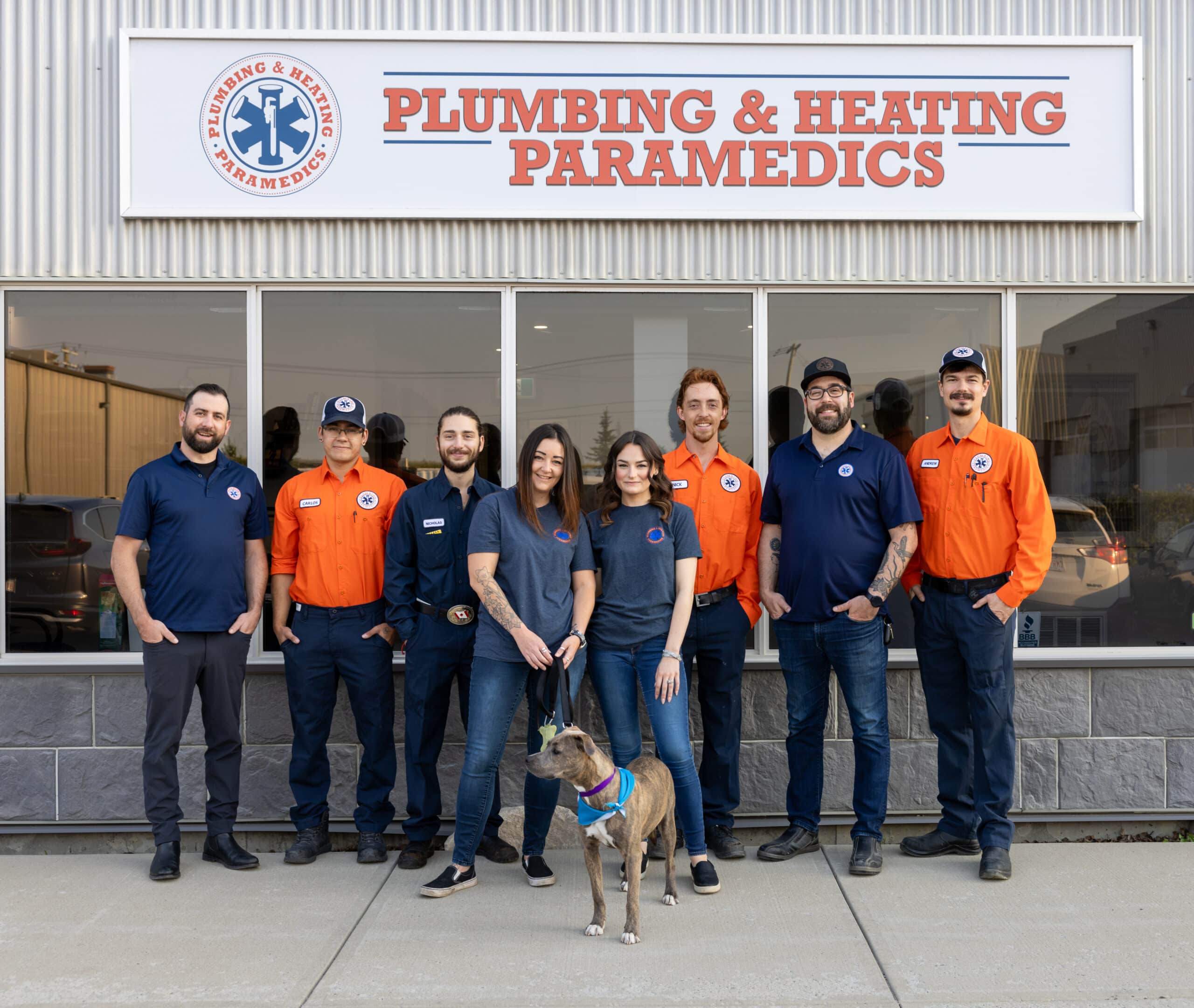 A group photo of eight employees dressed in company uniform stands in front of their company