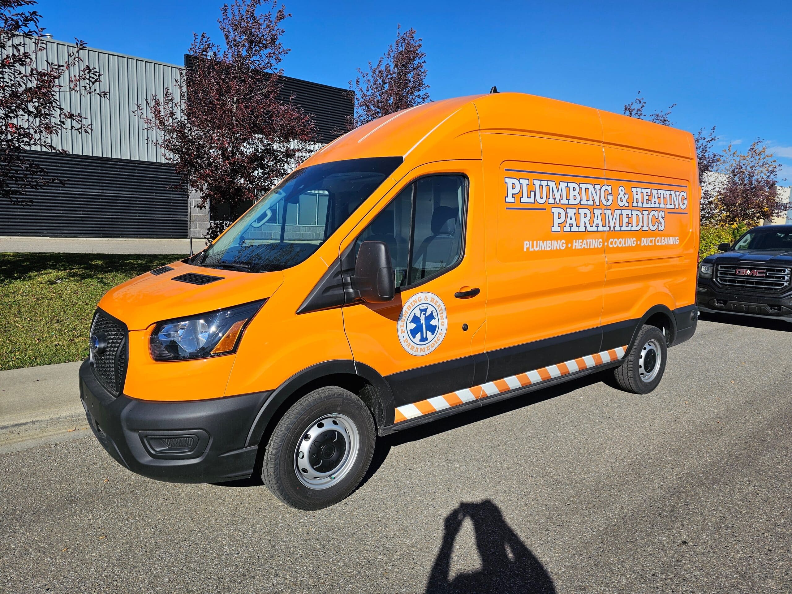 A company van is parked near a street under clear skies.